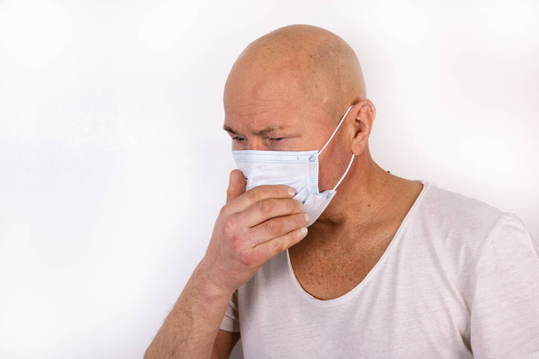 A sick man in a medical mask stands on a white background. The concept of protection against viral infection. - Fotoğraf, Görsel