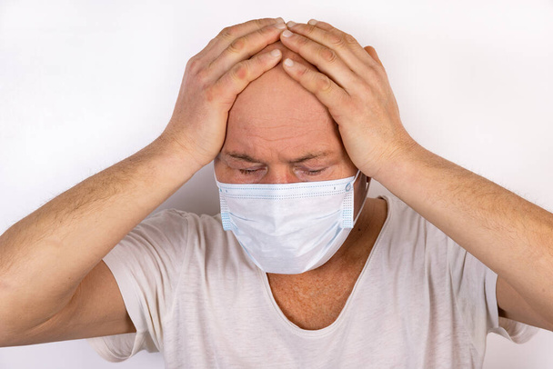 A sick man in a medical mask stands on a white background. The concept of protection against viral infection. - Fotoğraf, Görsel