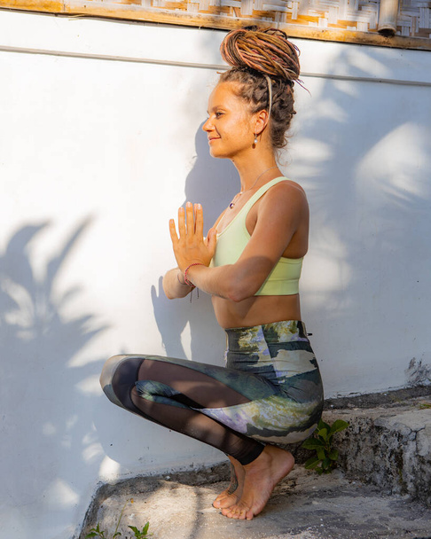 Namaste mudra. Yoga-Konzept. Balance und Konzentration. Junge Frau sitzt auf der Treppe. Meditation und Pranayamapraxis. Yoga-Retreat auf Bali. Frauenprofil. In der Nähe von Thomas beach. - Foto, Bild