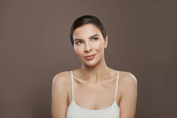 Healthy woman with clear skin looking up on brown background - Foto, imagen