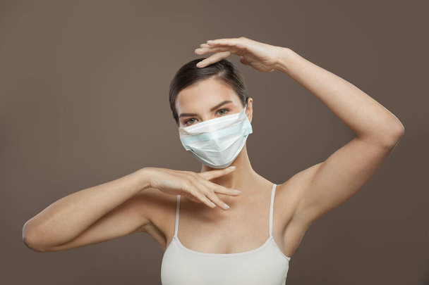 Mujer modelo saludable en máscara protectora sobre fondo marrón - Foto, imagen