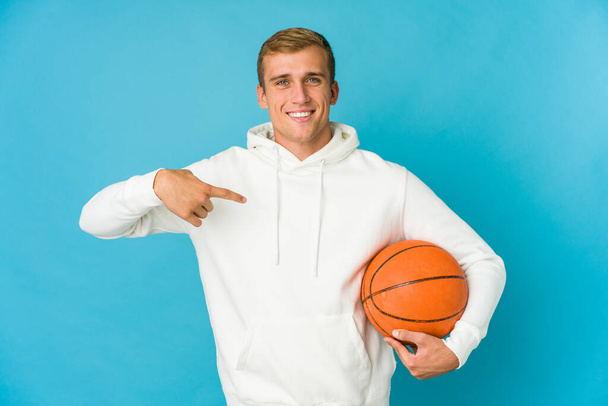Giovane uomo caucasico che gioca a basket isolato su sfondo blu mordere le unghie, nervoso e molto ansioso. - Foto, immagini