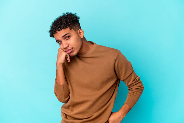 Jeune homme frisé afro-américain isolé sur bleu qui se sent triste et coûteux, en regardant l'espace de copie. - Photo, image