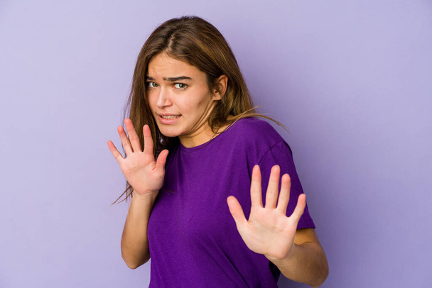 Молода худа біла дівчина підліток на фіолетовому фоні відкидає когось, хто показує жест огиди
. - Фото, зображення