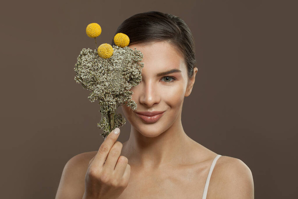Mujer feliz con flores. Spa, tratamiento facial, fitoterapia y cuidado de la piel - Foto, imagen