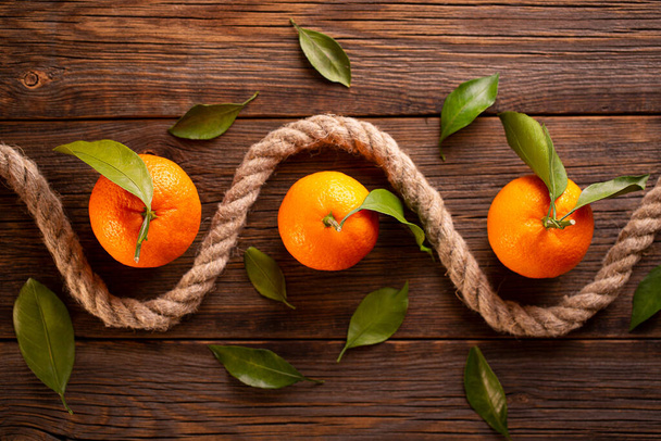 Ripe tangerines and rope on a wooden background. Abstract composition with a rope and tangerines. - Valokuva, kuva