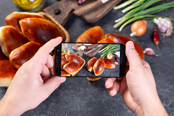 Kezek az okos telefonos képekkel az ételről. Főzés blogger főzés az otthoni konyhában a napsütéses napon, és hogy a fénykép az okostelefon. - Fotó, kép