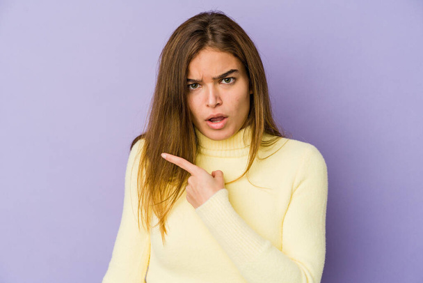 Young skinny caucasian girl teenager on purple background pointing to the side - Foto, imagen