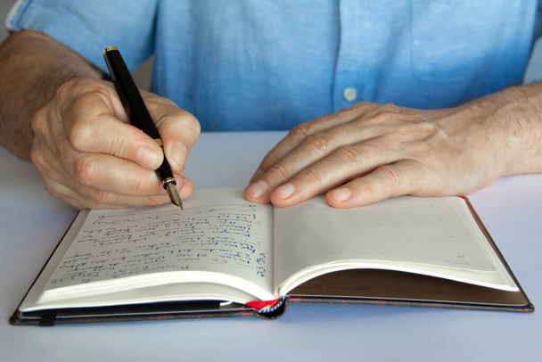 Main avec stylo et bloc-notes écrit. - Photo, image