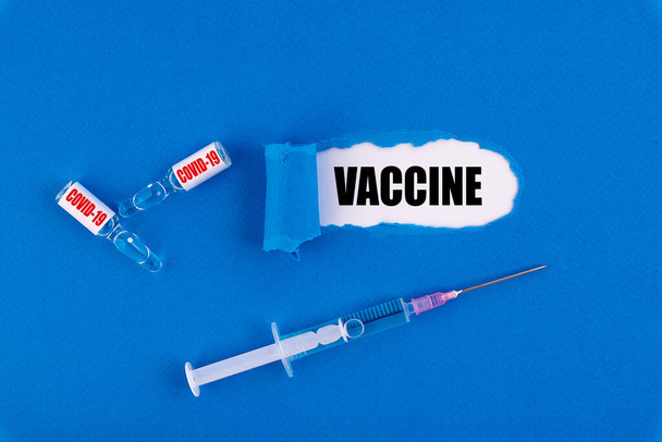 COVID-19 vaccine and syringe for injection lie on a blue background. Used for the prevention, immunization and treatment of COVID-19. - Fotó, kép