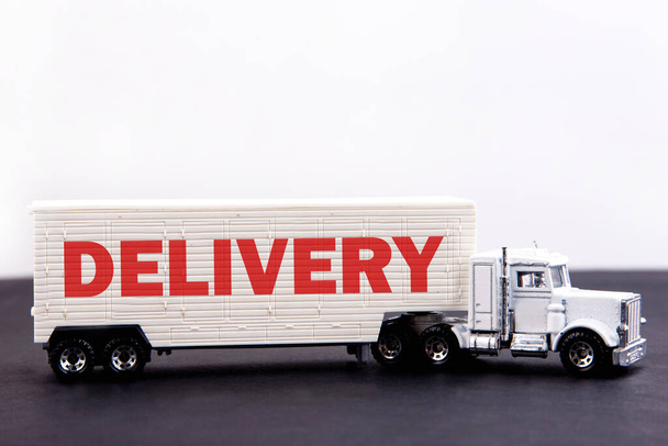 Delivery word concept written on board a lorry trailer on a dark table and light background - Fotografie, Obrázek