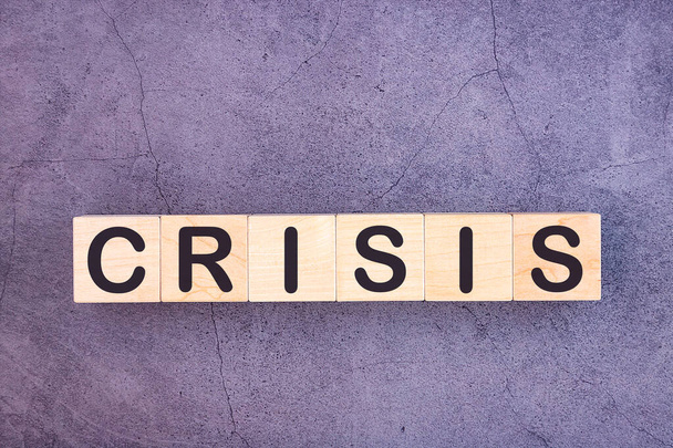 Word CRISIS is made of wooden building blocks lying on a grey background. - Foto, Bild