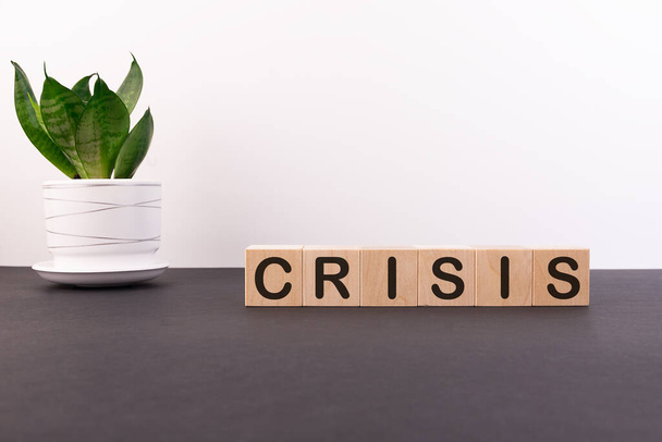 Word CRISIS is made of wooden building blocks lying on a black table and on a light background. - Foto, imagen