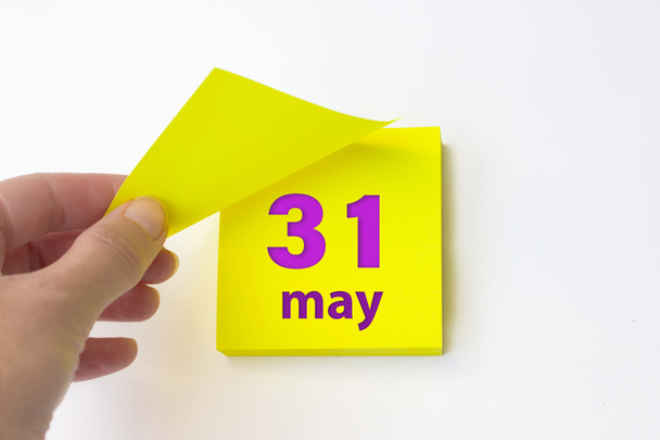 31 мая. день 31 месяца, календарная дата. Рука отрывает желтый лист календаря. Концепция "весенний месяц, день года" - Фото, изображение