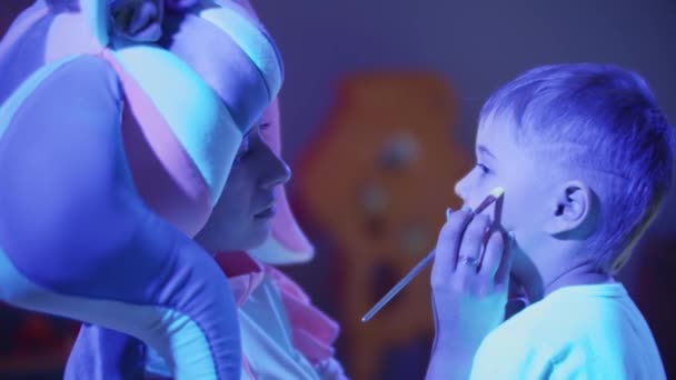 Animatore disegna illuminazione al neon sulla guancia dei ragazzi - Filmati, video