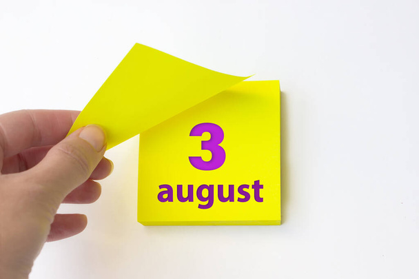 August 3rd. Day 3 of month, Calendar date. Hand rips off the yellow sheet of the calendar. Summer month, day of the year concept - Foto, afbeelding