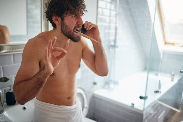 Dissatisfied topless man fighting while brushing teeth in the morning - Foto, imagen