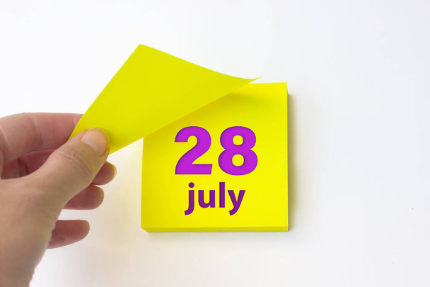le 28 juillet. jour 28 du mois, date du calendrier. arrache à la main la feuille jaune du calendrier. mois d'été, concept de jour de l'année - Photo, image