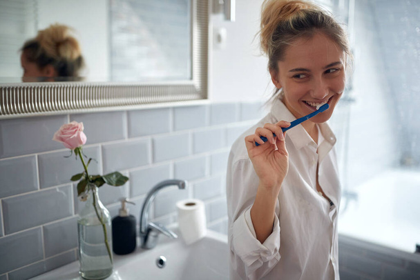 Cute blond woman brushing teeth in bathroom - Zdjęcie, obraz