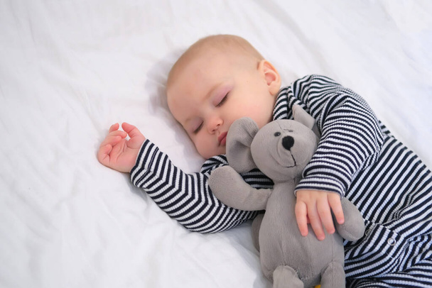 Спляча дитина з улюбленою м'якою іграшковою мишкою в смугастій піжамі. Портрет крупним планом, вибірковий фокус
 - Фото, зображення