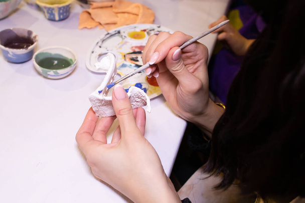 una chica pinta un producto de arcilla en el taller - Foto, imagen