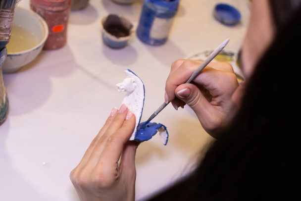 a girl paints a clay product in the workshop - Photo, Image