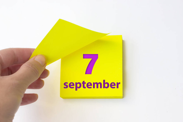 7 сентября. день 7 месяца, календарная дата. Рука отрывает желтый лист календаря. осень месяц, день года концепция - Фото, изображение