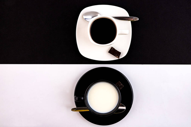 A black cup and saucer on a white background and a white cup and saucer on a black background. The concept of opposites and connections. - Zdjęcie, obraz