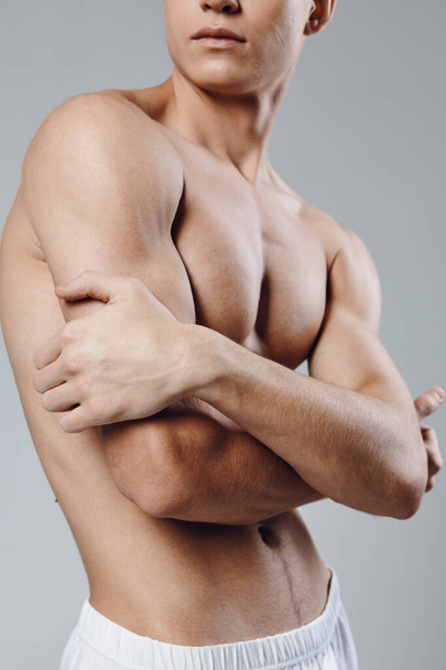 athletic man with pumped up arm muscles hugging himself with his arms and looking to the side  - Foto, Bild