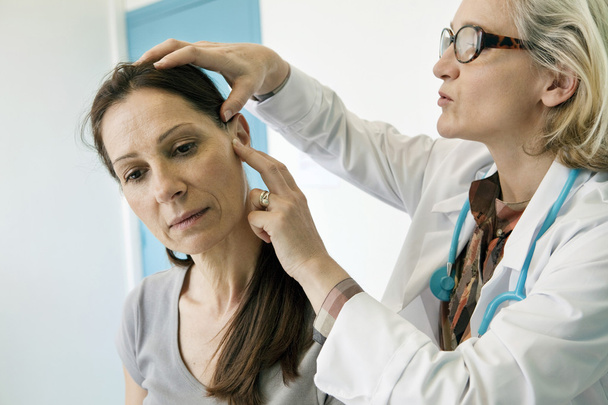 Doutor examina o ouvido da mulher
 - Foto, Imagem