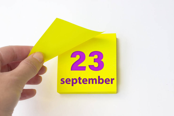 23 сентября. день 23 месяца, календарная дата. Рука отрывает желтый лист календаря. осень месяц, день года концепция - Фото, изображение