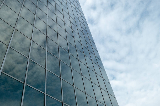 A low angle shot of the reflection of the fluffy clouds on a modern building - Foto, Bild