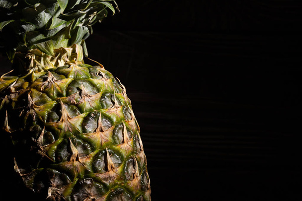 Whole pineapple on a wooden texture background. Spot light. - Photo, image