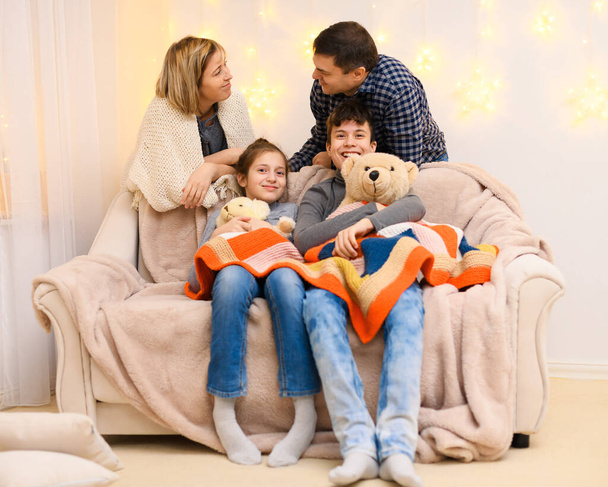 portrait d'une famille assise sur un canapé à la maison, quatre personnes s'amusent ensemble. - Photo, image