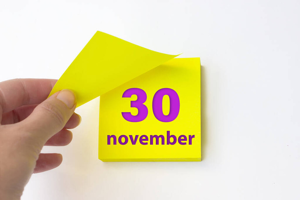 November 30th. Day 30 of month, Calendar date. Hand rips off the yellow sheet of the calendar. Autumn month, day of the year concept - Photo, Image