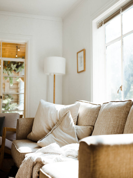 Ένα κατακόρυφο κοντινό πλάνο ενός άνετου καναπέ σε ένα σπίτι σχεδιασμένο σε λευκά χρώματα - διακόσμηση εσωτερικών χώρων - Φωτογραφία, εικόνα