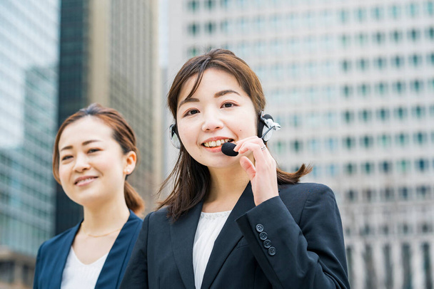 Mujer de negocios asiática con auriculares en el distrito de negocios - Foto, Imagen