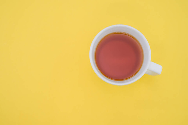 A top view of a white cup of tea isolated on yellow background - Photo, Image