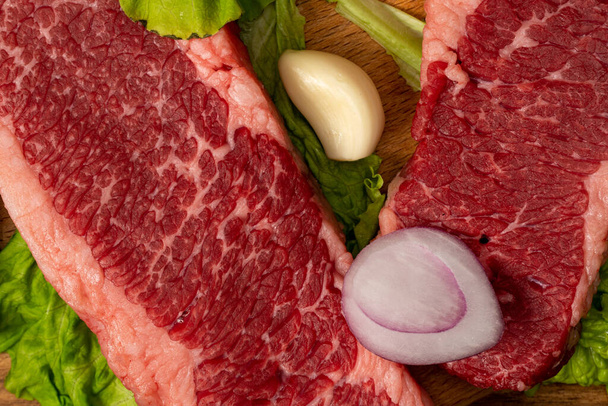 Syrové mramorované hovězí steaky se salátem, červenou cibulí, česnekem a okurkou. - Fotografie, Obrázek