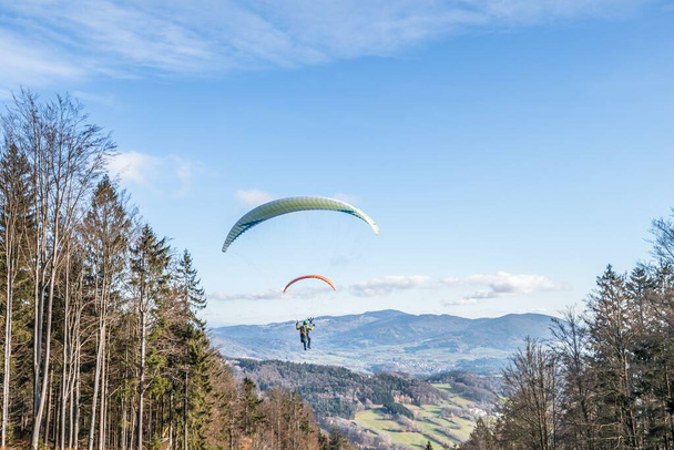 Latający pilot paralotni hobby na zboczu góry z profesjonalnym sprzętem jesienią z widokiem na góry i Alpy w tle, Niemcy - Zdjęcie, obraz