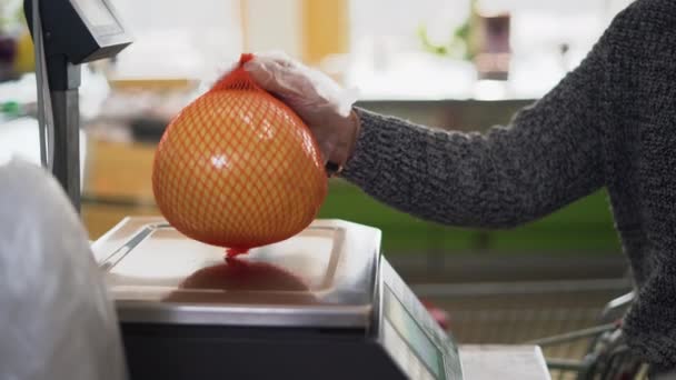 Una donna pesa un pomelo di agrumi o pompelmo nel negozio sulla bilancia. Concetto self-service - Filmati, video