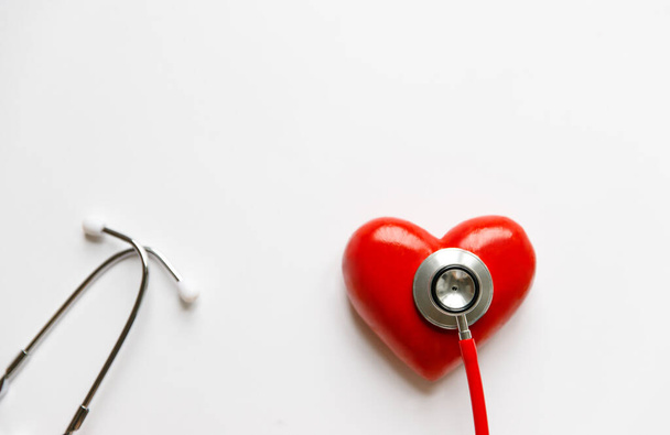 Detailní záběr stetoskopu na červeném srdci - lékařské diagnostické zařízení pro auscultaci (poslech) zvuků vycházejících ze srdce, bronchi. Izolováno na bílém pozadí s kopírovacím prostorem.  - Fotografie, Obrázek