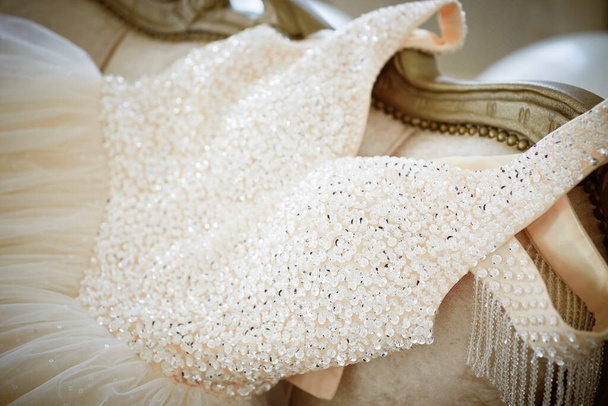 elegant wedding dress, embroidered with beads and crystals spread out on a vintage sofa. details, preparation for the wedding - Foto, afbeelding