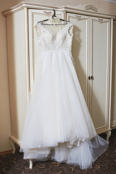 elegant wedding dress, embroidered with beads hanging on a vintage wardrobe. details, preparation for the wedding - Foto, Imagem