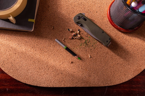 Кишеньковий ніж складений на стіл. Олівець і стружка. Верхній
. - Фото, зображення