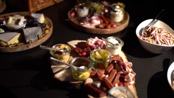 Composition of dishes. Slicing of smoked meats and various sori of cheese on a dark background. - Footage, Video