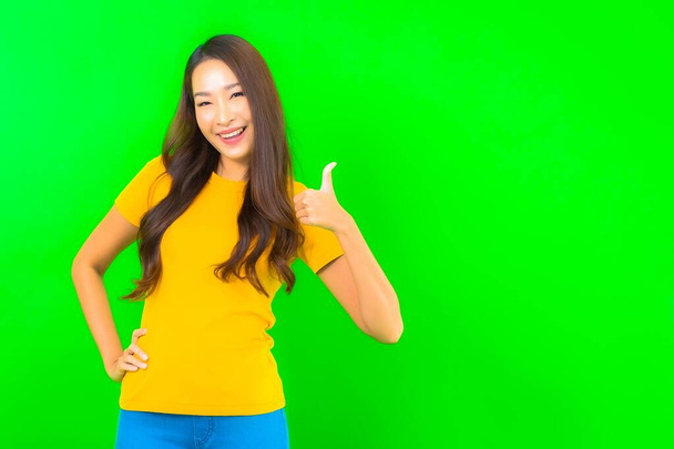 Портрет красивая молодая азиатская женщина улыбка с действием на зеленом изолированном фоне - Фото, изображение