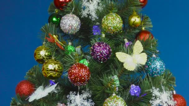 Weihnachtsbaum geschmückt mit bunten Kugeln auf blauem Hintergrund - Filmmaterial, Video