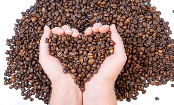 kahvipavut lähikuva kämmen muotoinen sydän taustaa vasten muita kahvipapuja - Valokuva, kuva