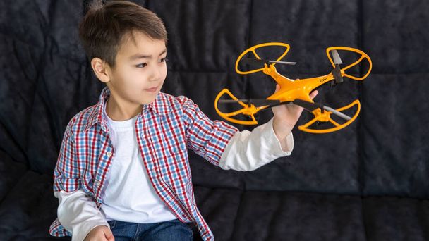 A small child will play at home with a quadcopter. The boy is holding a radio control. home life style. - Foto, immagini
